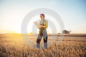 Farmer woman and combine harvester on wheat field