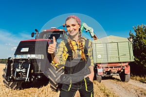 Farmer woman in front of agricultural machinery giving thumbs-up