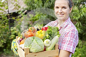 Farmer woman in gloves holding wooden box full of fresh raw vegetables. Basket with vegetable in the hands