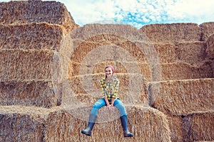 Farmer woman having break on bale of straw