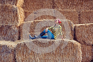 Farmer woman having break on bale of straw