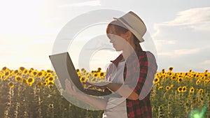Farmer woman working in the field. agronomist in a field of sunflowers with a laptop works in the sun. business woman