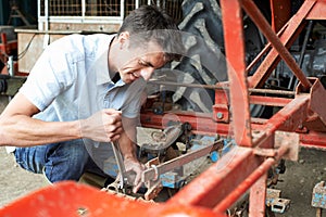 Farmer Working On Agricultural Equipment In Barn