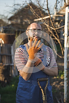 Farmer working in the garden with the help of a rake leveling plowed land, on a sunny day