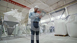 Farmer working on a laptop and standing in front of bags of flour at grain storage