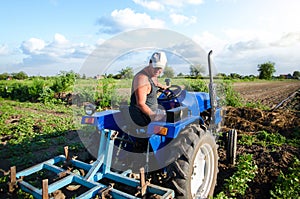 The farmer works in the field with a tractor. Agroindustry and agribusiness. Farm field work cultivation. Farming machinery.