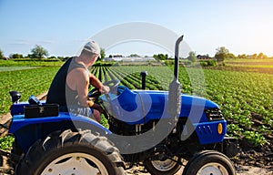 Farmer works in the field with a tractor. Agroindustry and agribusiness. Farm machinery. Crop care, soil quality improvement.