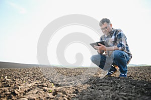 The farmer works on the ground. Male farmer on a plowed field, planting cereals in the spring in the ground