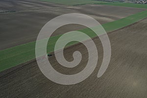 The farmer works with the tractor during the early spring season. Aerial view of mounted tractor while working