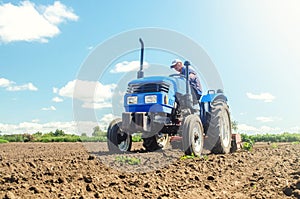 The farmer works on a tractor. Loosening the surface, cultivating the land for further planting. Cultivation technology equipment