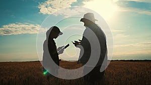 Farmers handshake over the wheat crop in harvest time. Team farmers stand in a wheat field with tablet. Partnership