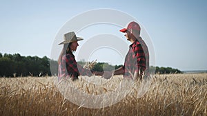 Farmers handshake over the wheat crop in harvest time. Team farmers stand in a wheat field with tablet. Partnership