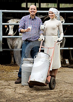 Farmers holding large metallic milk cans