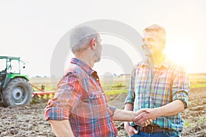 Farmers shaking hands after agreement against combine harvester in field