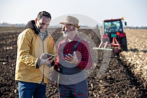 Farmers talking in field in front of tractor in autumn