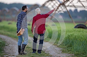 Farmers walking next to field pointing at center pivot irrigation system