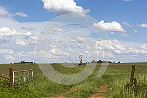 Farmgate and a windpump with clouds