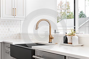 A farmhouse sink with a gold faucet in a luxury kitchen.
