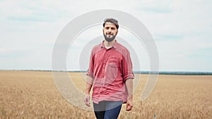 Farming and agriculture concept guy farmer walking through the wheat field and happy looking around feeling great to see