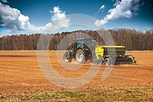 Farming - farmer with tractor on the field seeding sowing crops