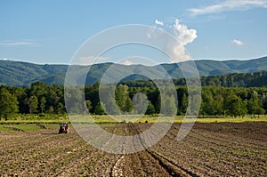 Farming with tractor and plow in field with mountain Papuk in th