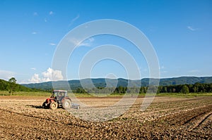 Farming with tractor and plow in field with mountain Papuk in th