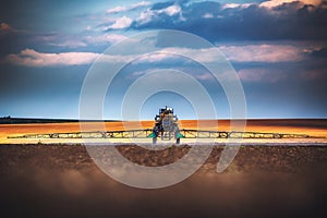 Farming tractor plowing and spraying on field photo