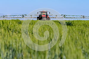 Farming tractor plowing and spraying on field.