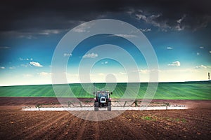 Farming tractor plowing and spraying on field