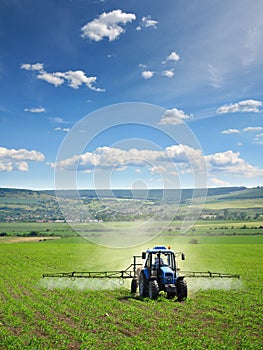 Farming tractor plowing and spraying on field photo