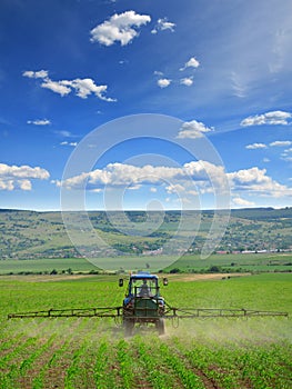 Farming tractor plowing and spraying on field