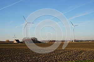 Farmland with farmer\'s farm. Bare agricultural landscape of food industry in winter season. Windmills in the background.