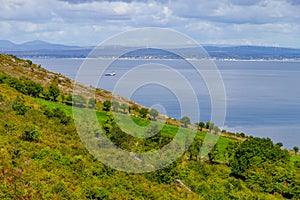 Farms in Burren way trail with Galway bay and boat in background