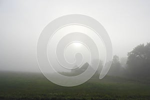 Farmstead visible through foggy morning sunlight photo