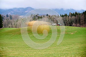 Farmworker spreading liquid manure on grassland