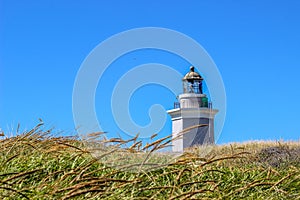 Faro Los Morrillos lighthouse in Cabo Rojo against behind the grass against the blue sky