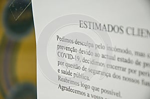 Faro, Portugal - March 16, 2020: Printed message on the front window of a shop written in Portuguese language informing people