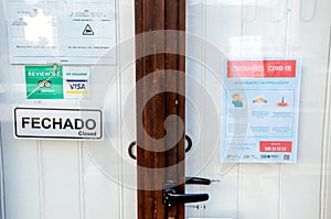 Faro, Portugal - March 16, 2020: Closed front door of the restaurant with coronavirus safety instructions leaflet in Portuguese