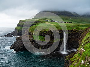 Faroe Islands. MÃÂºlafossur Waterfall and Gasadalur village over the the waterfall. Long exposure. photo