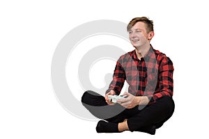 Fascinated teenager boy seated on the floor playing video games isolated on white background. Excited adolescent holding a