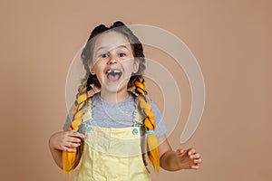 Fascinated young nice female holding yellow kanekalon pigtail with hand, smiling with missing tooth looking at camera