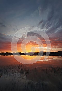 Fascinating sunset reflecting on the lake surface. Idyllic landscape, vertical background. Silent and tranquil evening scene with