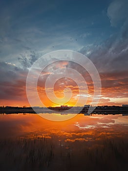 Fascinating sunset reflecting on the lake surface. Idyllic landscape, vertical background. Silent and tranquil evening scene with