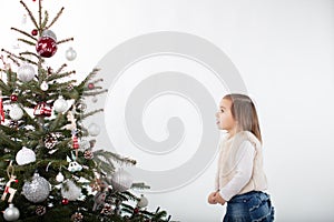 Fascinnated toddler girl looking up towards Christmas Tree