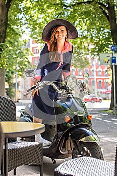 Fashin girl sitting on street scooter.