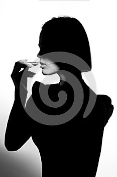 Fashion advertising portrait of a young beautiful girl using lipstick. Black and white silhouette with epic light.