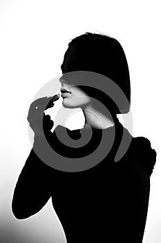 Fashion advertising portrait of a young beautiful girl using lipstick. Black and white silhouette with epic light.