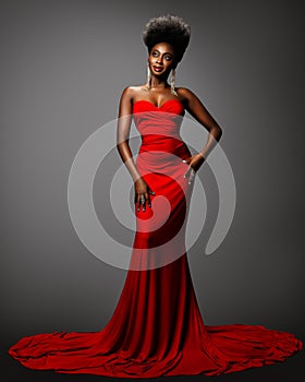 Fashion Afro American Woman in Red Sexy Dress. African Model with Afro Hairstyle in Long Evening Gown over Gray background.