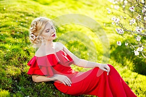 Fashion Art Beauty Portrait. Beautiful Girl in Fantasy Mystical and Magical Spring Garden. Model Woman wearing Long red