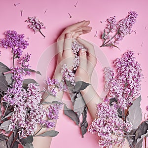 Fashion art hands natural cosmetics women, bright purple lilac flowers in hand with bright contrast makeup, hand care. Creative